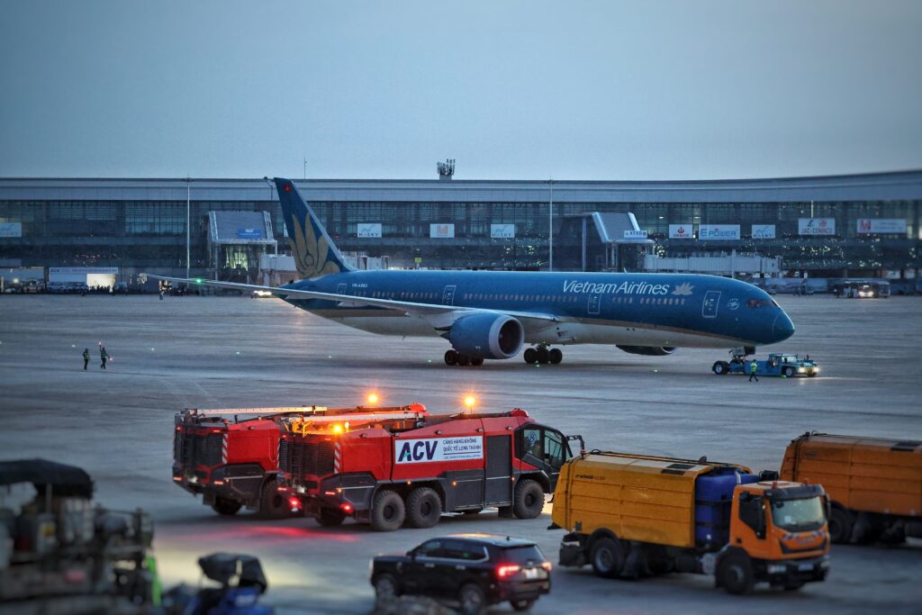 Vietnam Airlines Boeing 787 at Noi Bai Airport with service vehicles at twilight.